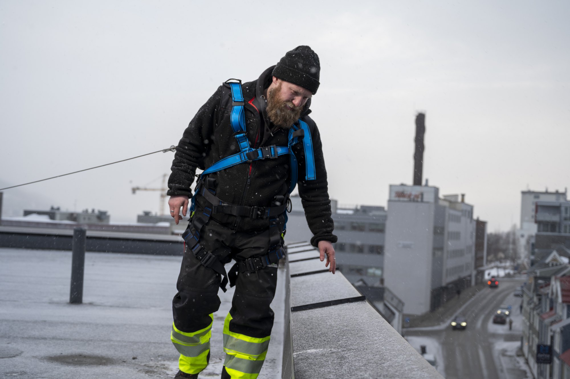 Medarbeider med fallsikringsutstyr under tilsyn på et tak